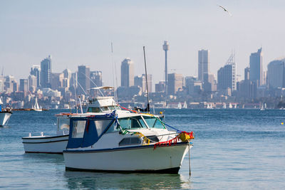 Nautical vessel on sea by buildings in city against sky