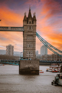 Tower bridge over river against sky during sunset