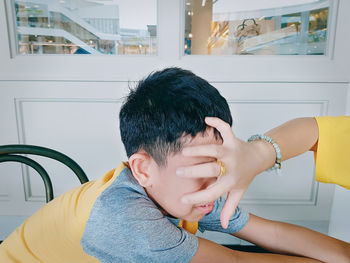 Close-up of hand pushing boy looking at home