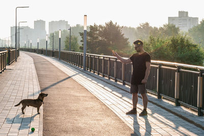 Young man is playing with his dog on empty street in the morning.