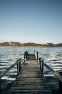 Pier over lake against clear sky