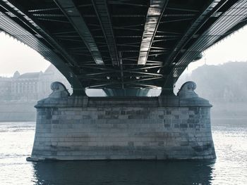 Bridge over river in city against sky