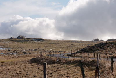 Wooden fence on landscape against sky