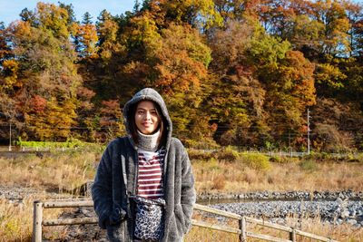 Portrait of a beautiful woman holding camera standing on field