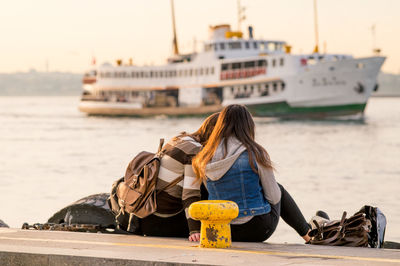 Rear view of friends sitting against sea