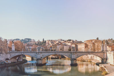 Bridge over river in city against clear sky