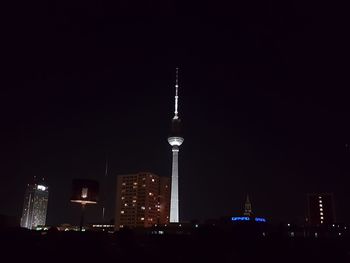 Communications tower in city against sky at night