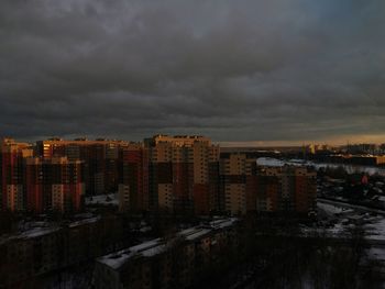 Buildings in city against storm clouds