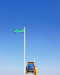 Low angle view of flag against clear blue sky