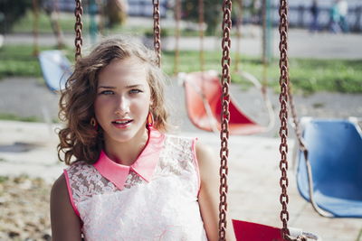 Portrait of young woman in swing at playground