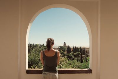 Rear view of woman standing in front of window