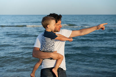 Father and son standing at sea shore