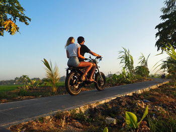 Man with girlfriend riding motorcycle on road against clear sky