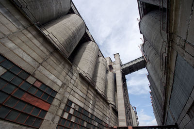 Low angle view of silos against cloudy sky