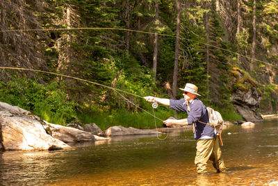 Man fishing in river at forest