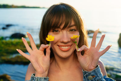 Portrait of a young woman holding flowers near her face