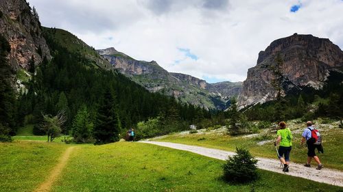 Rear view of people walking on mountain against sky