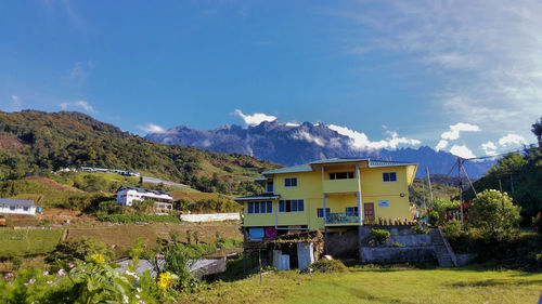 Houses by trees and buildings against sky
