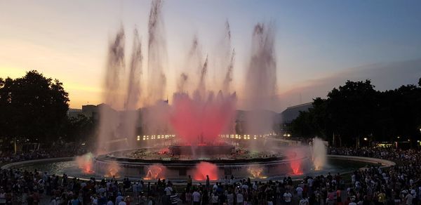 People at fountain against sky during sunset