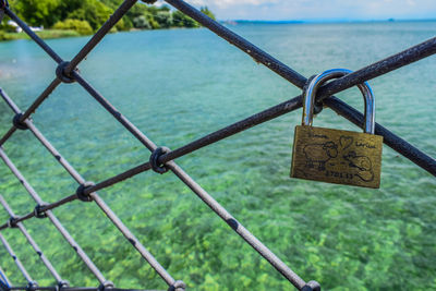 Close-up of padlocks on railing against sea