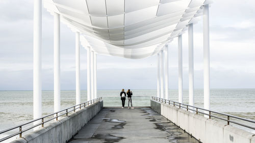 People standing on pier over sea