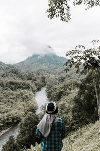 Rear view of hiker enjoying view of mountain during foggy weather