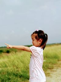 Happy girl standing on field against sky