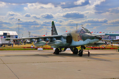 Airplane at airport runway against sky