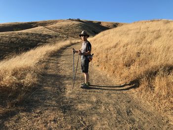 Side view of man standing on mountain against clear sky