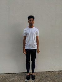 Full length portrait of young man standing against wall