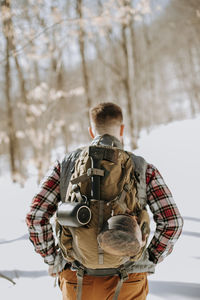 Closeup of man wearing pack and flannel in snow covered woods