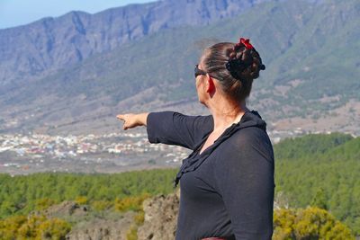 Rear view of woman pointing at mountains