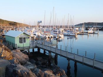 Boats moored on river by pier against clear sky