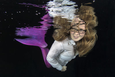 Portrait of smiling young mermaid woman swimming underwater