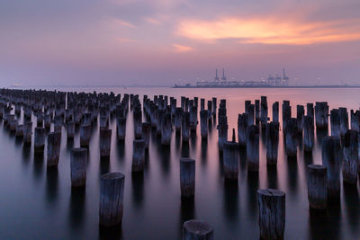 Scenic view of wooden posts in sea against sky