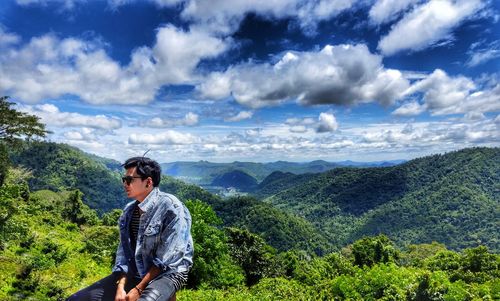 Young man looking at mountains against sky