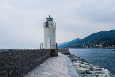 Lighthouse by sea against sky