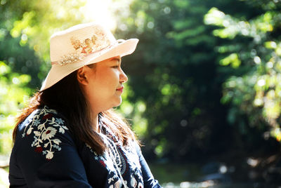 Close-up of woman wearing hat against trees