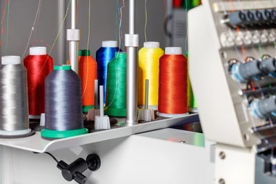 Multi-colored nylon threads in spools on a blurred background of an industrial embroidery machine.