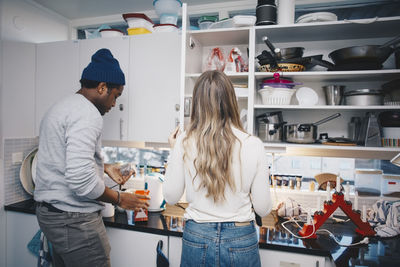 Rear view of roommates cooking in kitchen