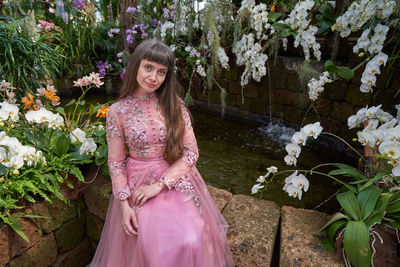 Portrait of woman standing by pink flowering plants