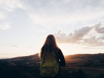 Rear view of woman standing on landscape against sky