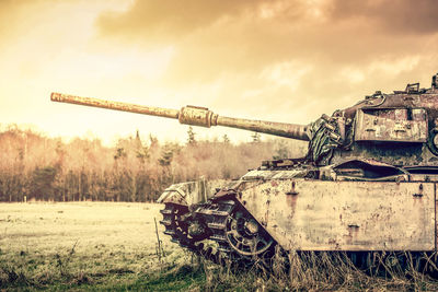 Abandoned armored tank on field against sky