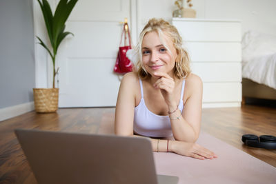 Portrait of young woman sitting on sofa at home