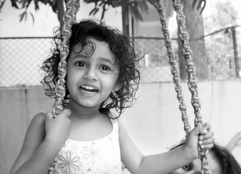 Smiling girl sitting on swing at park