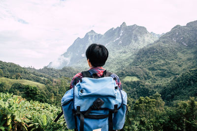 Rear view of man looking at mountains against sky