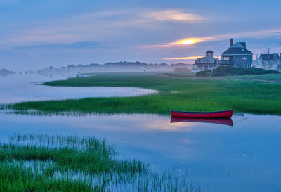 Red canoe floats in maine coast tidal inlet after sunset