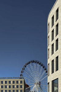 Low angle view of ferris wheel against buildings in city