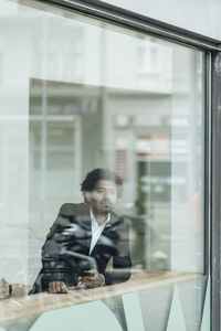 Full length of a young man looking through window