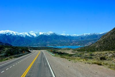 Road by mountains against clear blue sky